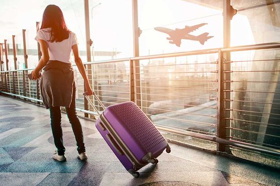 Junge Frau zieht Koffer im Flughafenterminal.